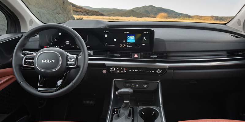 Interior view of a Kia dashboard with steering wheel, digital display, and center console.