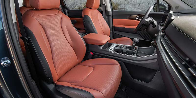 Front interior view of a Kia vehicle showing leather seats and center console.
