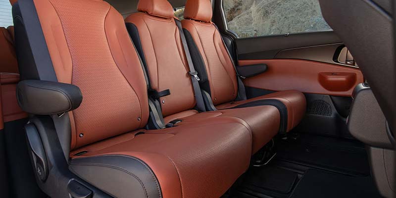 Rear bench seats in a Kia Carnival with leather upholstery.
