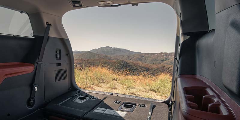 Kia Carnival cargo area with seats folded down, showing rear storage space.