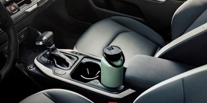Car center console with gear shifter and cup holder.