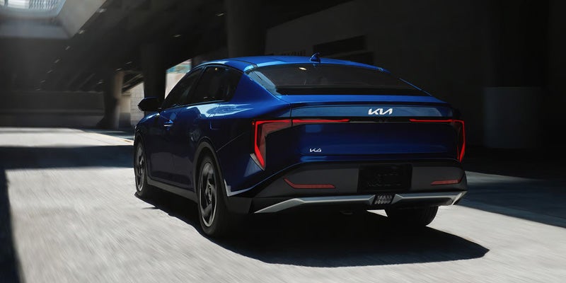 2026 Kia K4 compact sedan driving on a road.