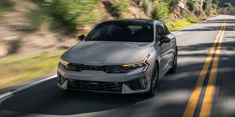 2026 Kia K5 sedan driving through scenic road